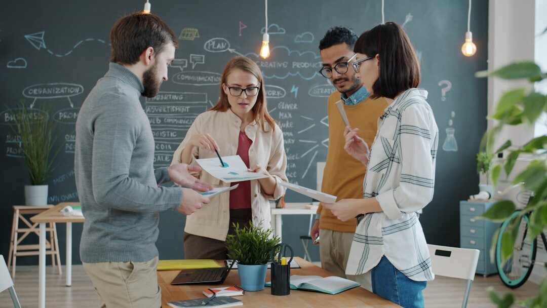 Modern startup office with young professionals collaborating around laptops and whiteboards